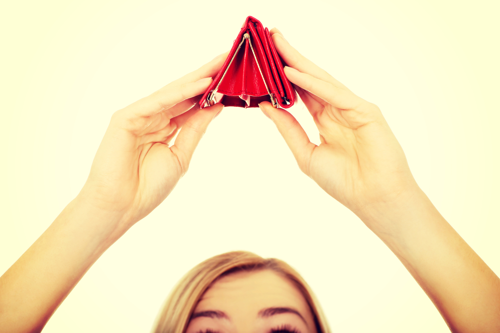 Frau hält eine leere Geldbörse verkehrt herum über ihren Kopf