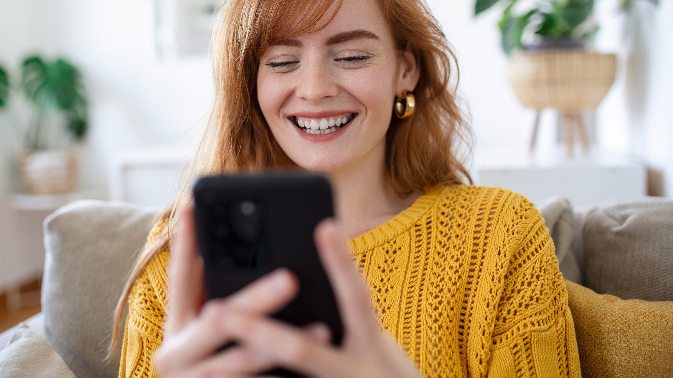 Eine junge Frau lacht und schaut auf ihr Handy