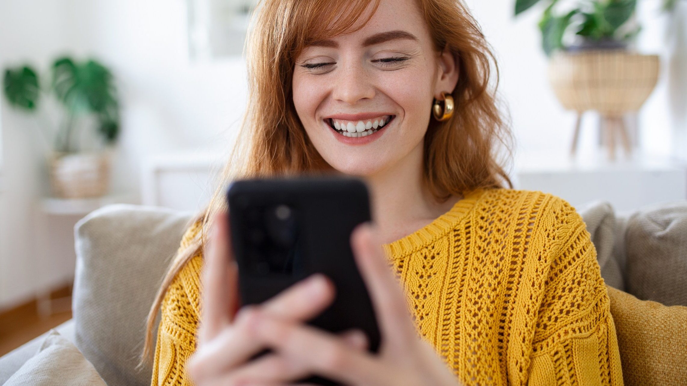 Eine junge Frau lacht und schaut auf ihr Handy