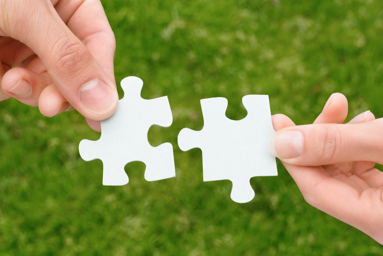 Zwei Hände, die zwei Puzzle-Stücke halten