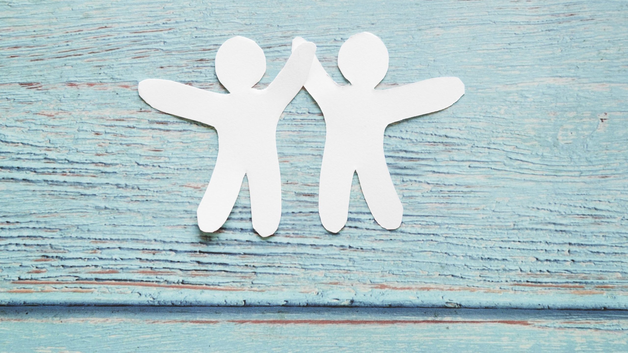 Zwei aus Papier ausgeschnittene Männchen geben sich High-Five