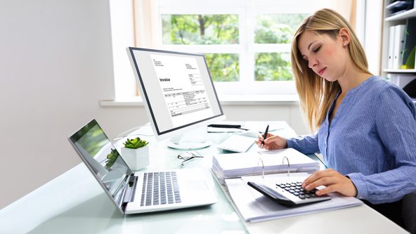 Frau sitzt am Schreibtisch in einem Büro vor einem Aktenordner