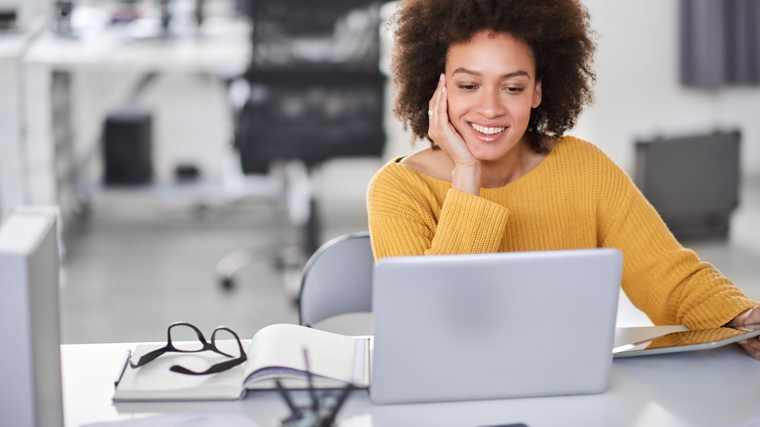 Frau sitzt lächelnd am Laptop