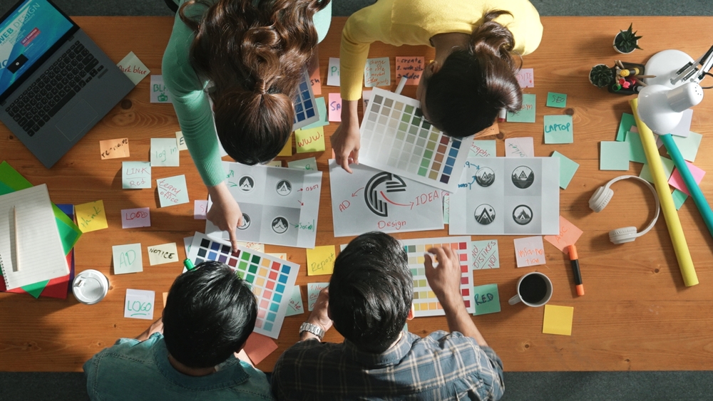 Eine Gruppe von Menschen ist über einen Tisch gebeugt und sucht kreative Lösungen