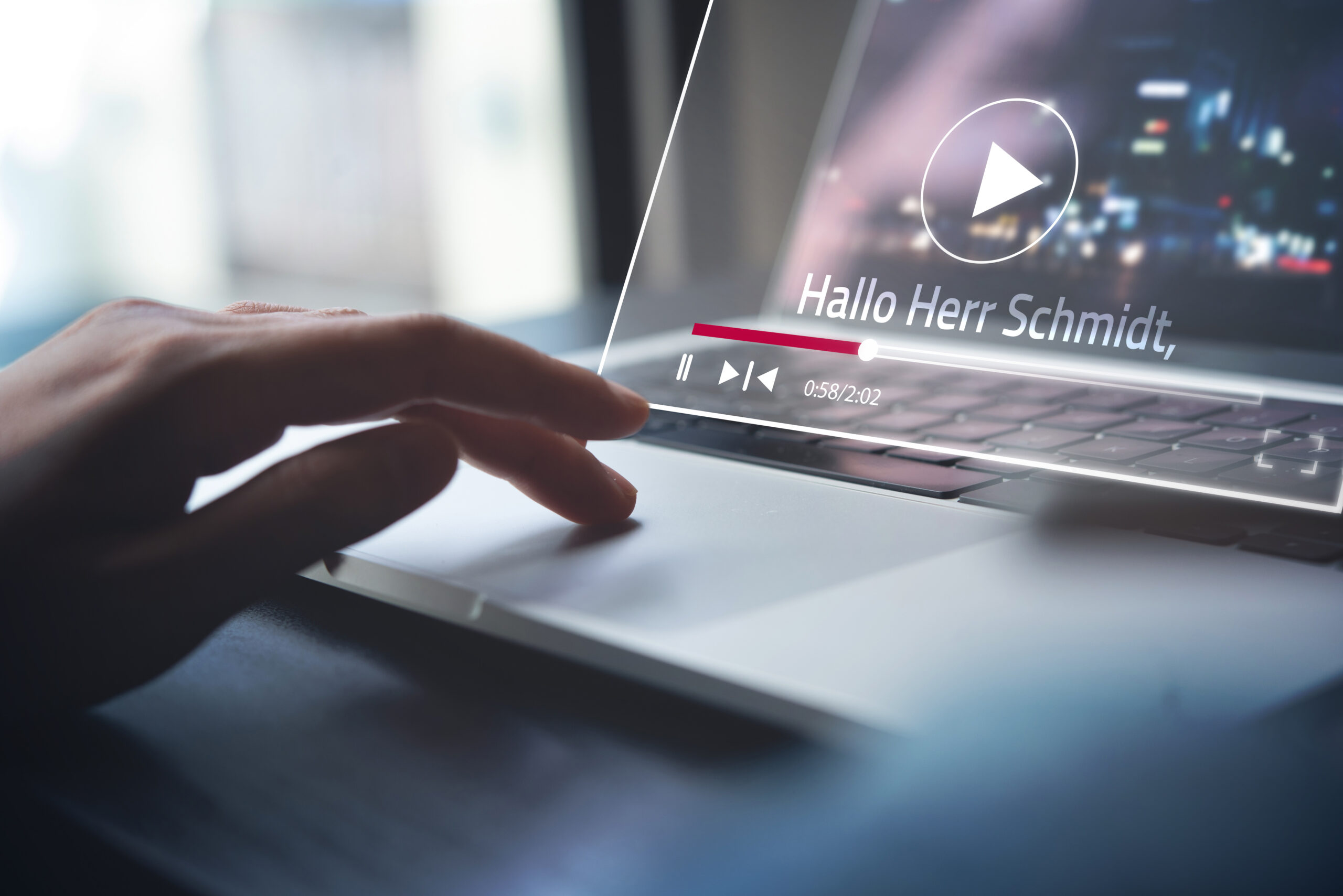 Eine Hand auf der Laptop-Tastatur. Am Bildschirm wird ein Video abgespielt
