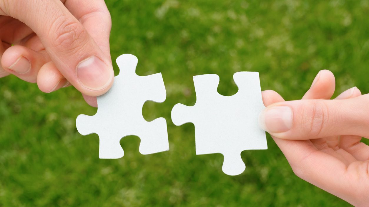 Zwei Hände, die zwei Puzzle-Stücke halten