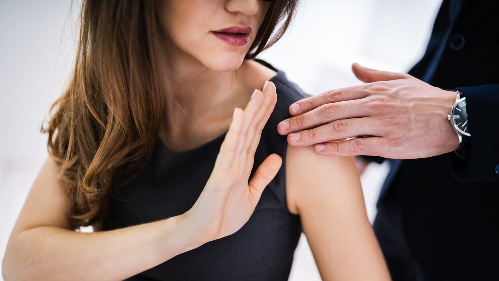 Ein Mann berührt eine Frau an der Schulter, die das zurückweist